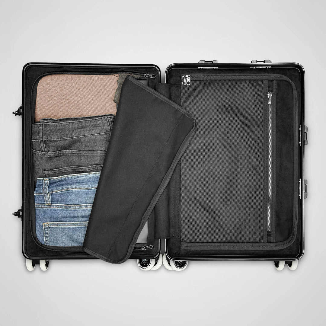 Black suitcase with clothes inside on a light gray background