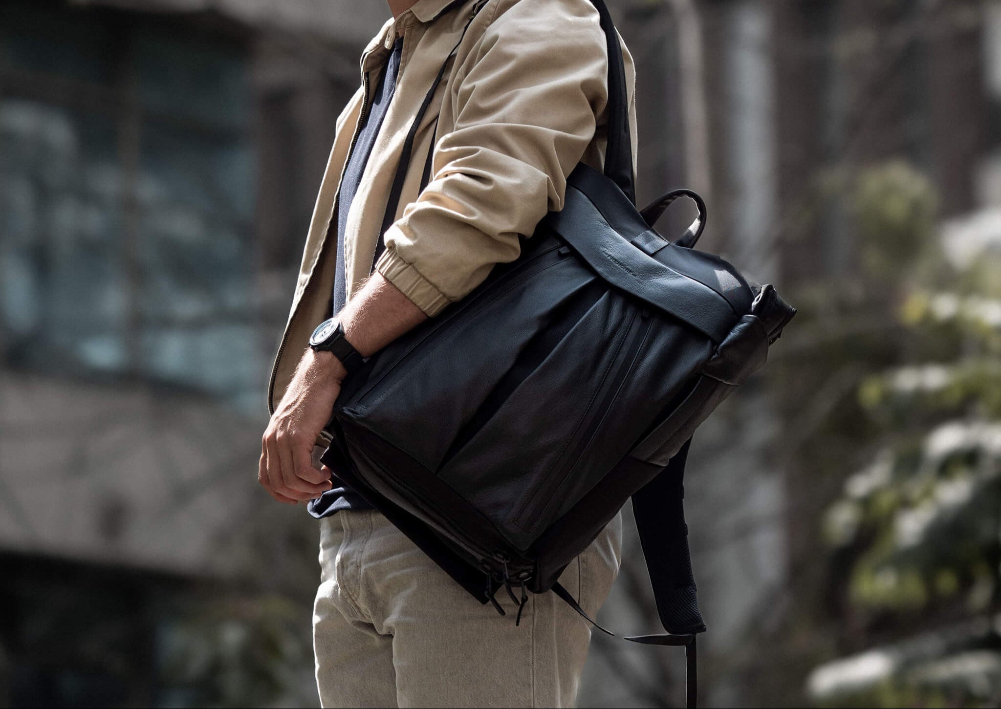 Person holding a black backpack with a blurred background