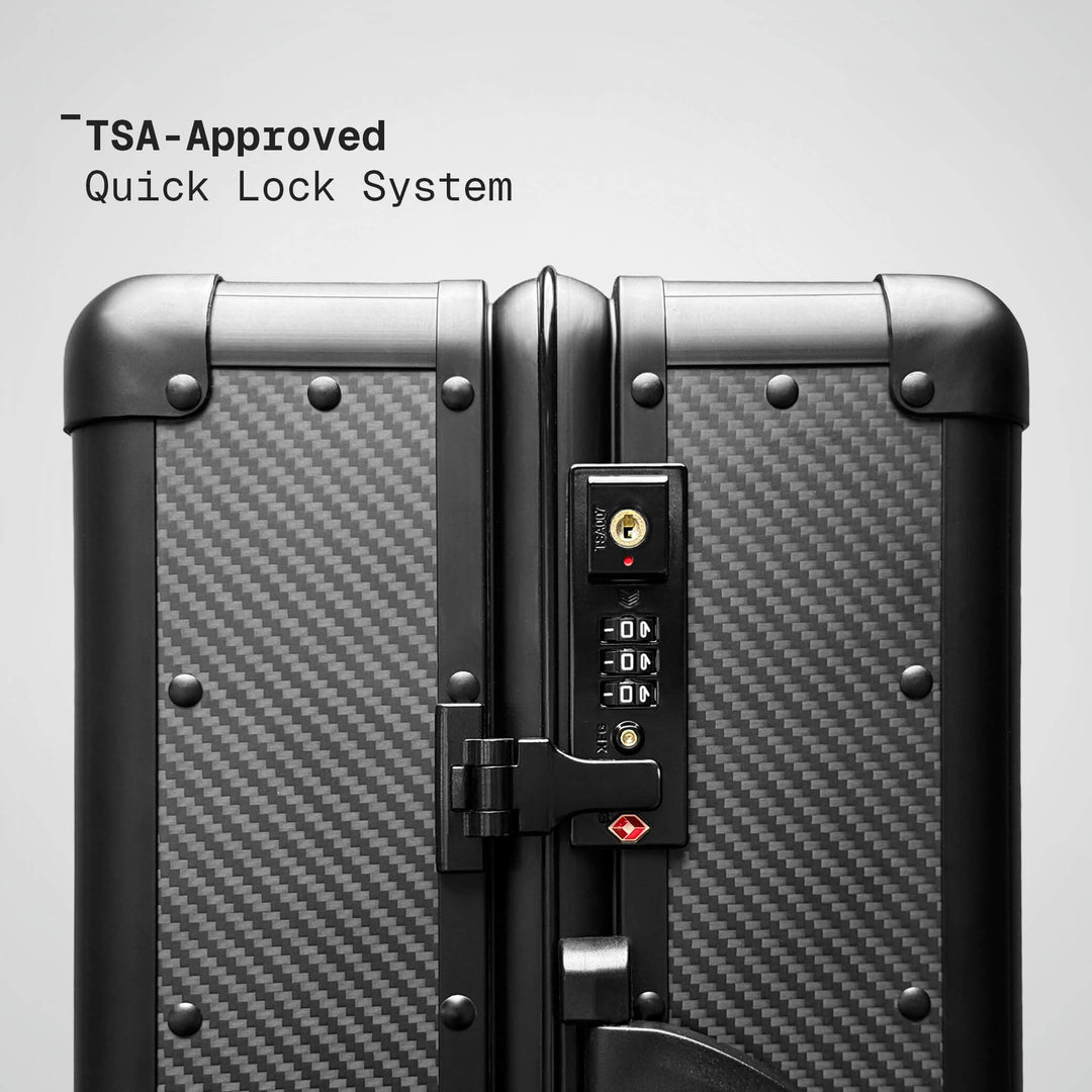 TSA-approved quick lock system on a suitcase with carbon fiber texture.