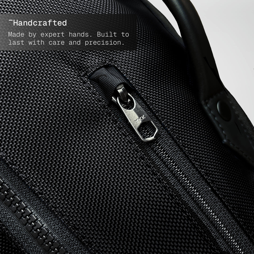Close-up of a black backpack zipper with text about craftsmanship.