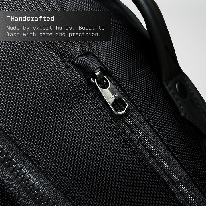Close-up of a black backpack zipper with text about craftsmanship.