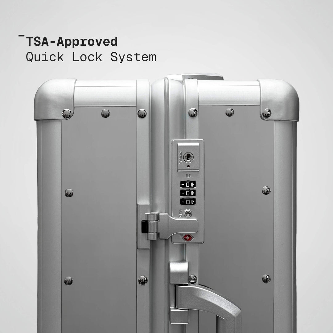 Silver suitcase with TSA-approved quick lock system on a light gray background