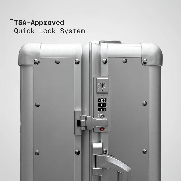 Silver suitcase with TSA-approved quick lock system on a light gray background