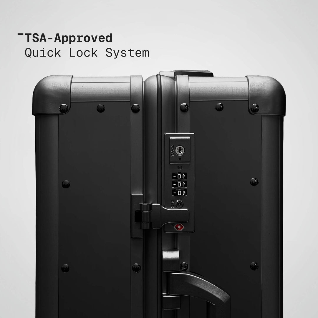 TSA-approved quick lock system on a black suitcase with a gray background