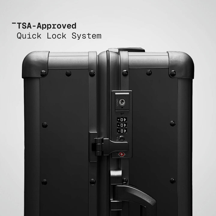 TSA-approved quick lock system on a black suitcase with a gray background