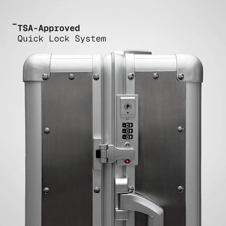 Silver suitcase with TSA-approved quick lock system on a light gray background