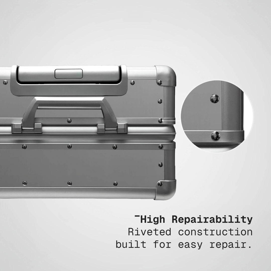 Silver suitcase with riveted construction feature on a light gray background