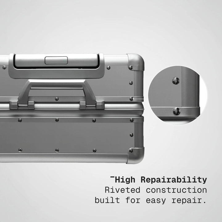 Silver suitcase with riveted construction feature on a light gray background