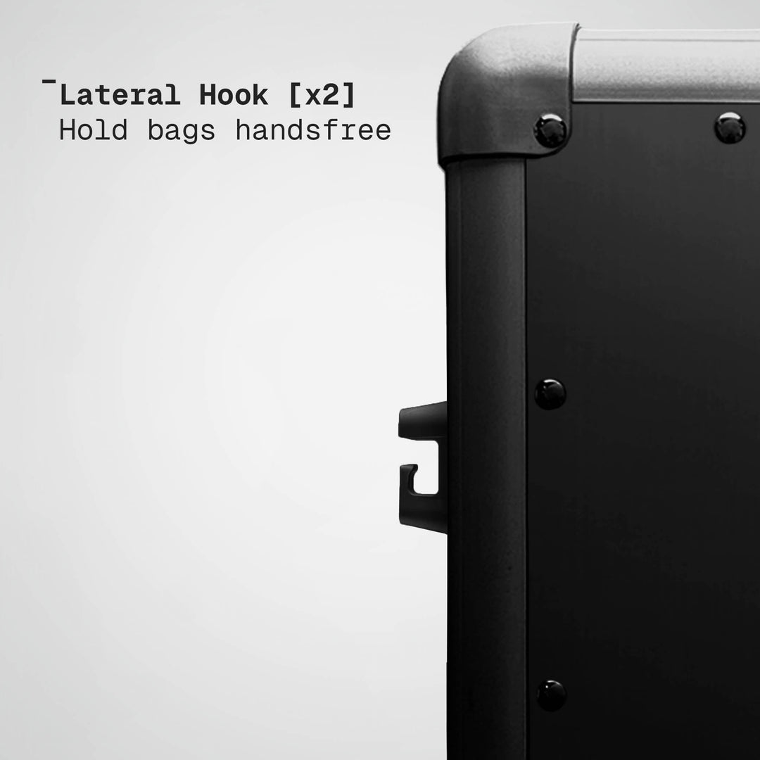 Lateral hook on a suitcase with text indicating it can hold bags handsfree.