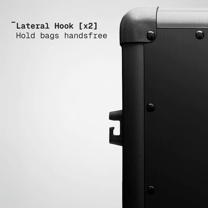 Lateral hook on a suitcase with text indicating it can hold bags handsfree.