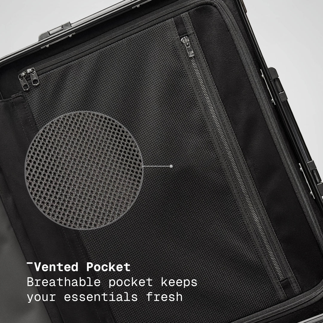 Black suitcase with a vented pocket feature on a gray background