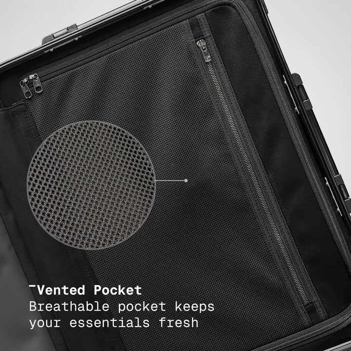 Black suitcase with a vented pocket feature on a gray background