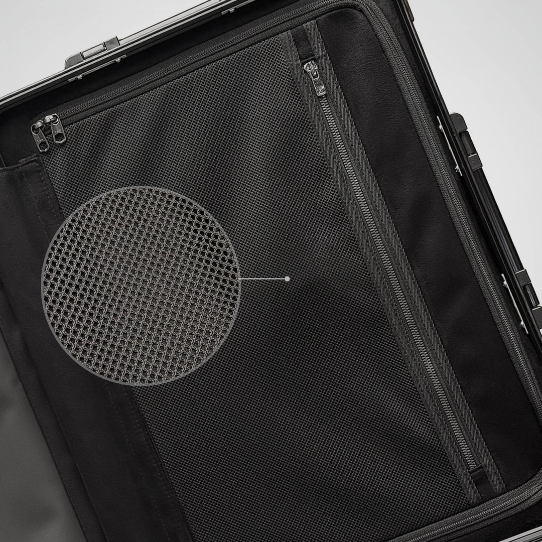 Close-up of a black suitcase with a circular mesh design on a light gray background