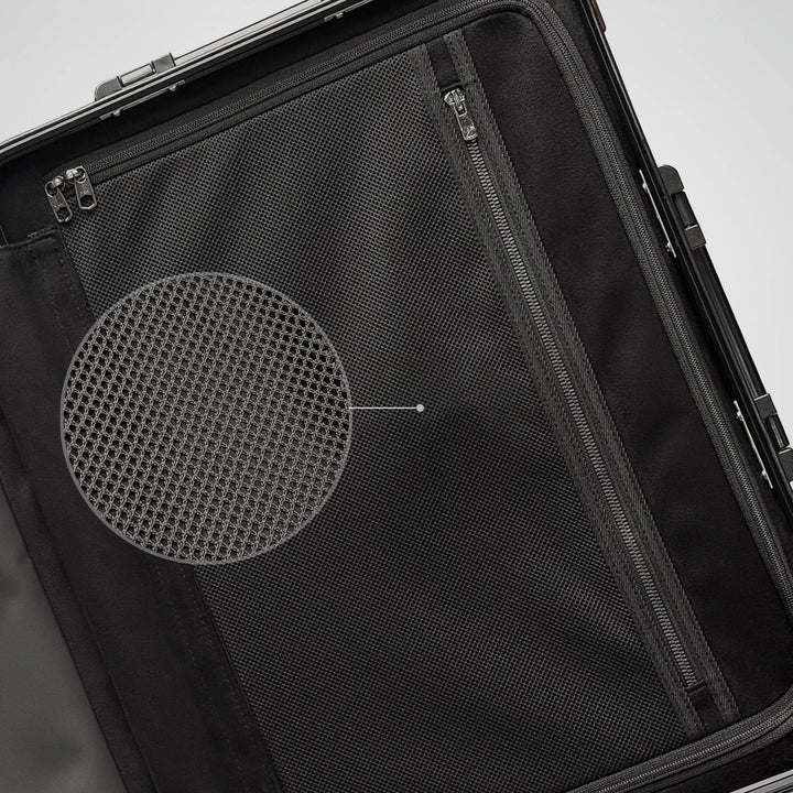 Close-up of a black suitcase with a circular mesh design on a light gray background